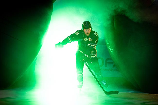 EIshockeyspieler der Starbulls Rosenheim fährt durch grünen Nebel